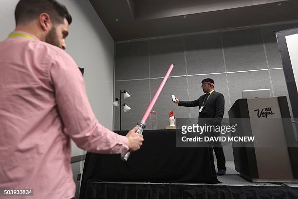 BrainCo CEO Bicheng Han wears the BrainCo Focus 1 to use bio feedback to turn on the light of a Star Wars light saber toy, held by a volunteer, by...