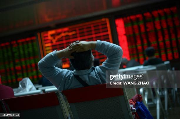 An investor looks at screens showing stock market movements at a securities company in Beijing on January 8, 2016. Chinese equities led another day...