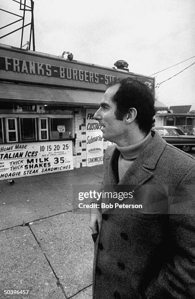 Author, Philip Roth, revisiting areas where he grew up in Newark, standing at hamburger stand.