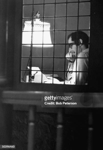 Author Philip Roth sitting at typewriter seen through panes of window, at Yaddo artist's retreat.