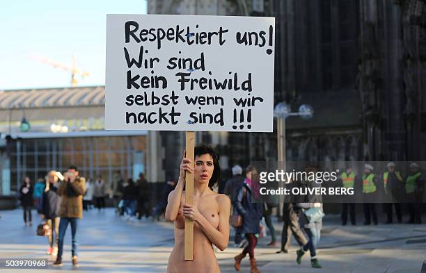 Performance artist Milo Moire holds up a poster reading "Respect us! We are no fair game, even when we are naked!!!" as she stands near Cologne's...