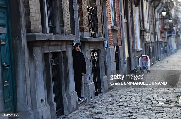 Picture taken on January 8, 2016 in the Brussels district of Schaerbeek shows a woman stepping out an apartment building in the Rue Henri Berge....