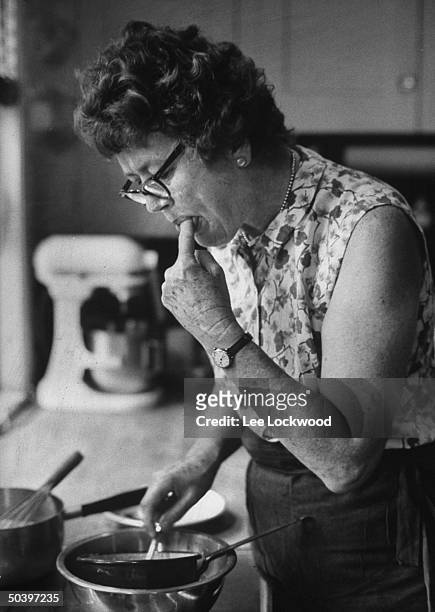 Cooking expert Julia Child tasting a concoction she is making at home.
