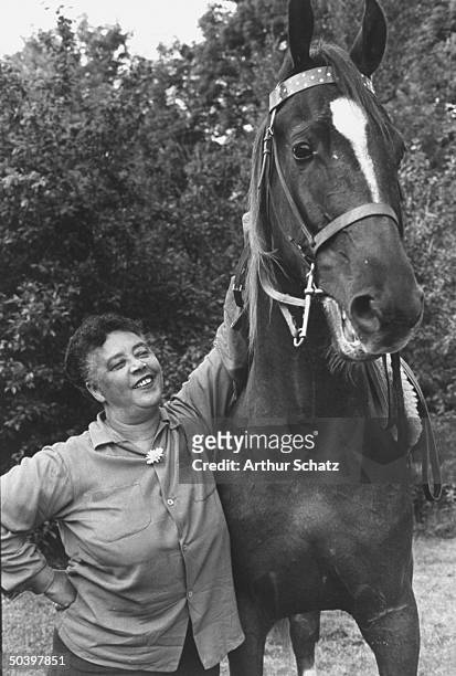 Nightclub singer Mabel Mercer standing by a horse on her farm.