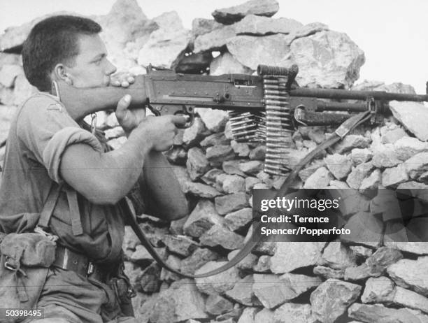 British Army paratrooper from a battalion of the Parachute Regiment fires a machine gun during fighting between rebel Qutaibi tribesmen, known as the...