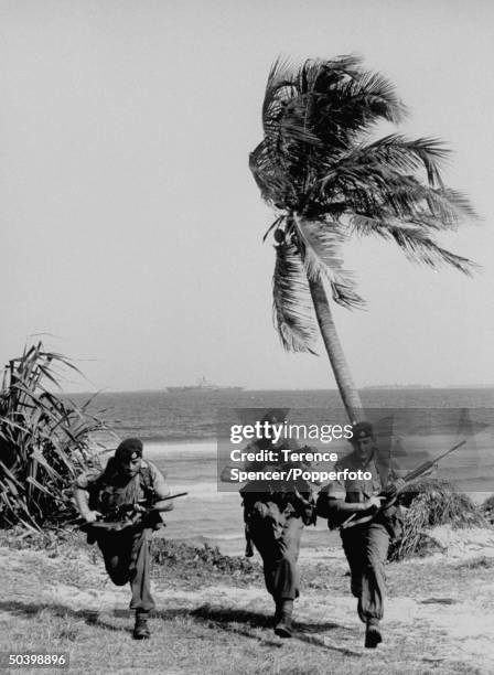 British Royal Marines from 45 Commando training on a beach in Tanganyika in January 1964. Visible in the background is the Royal Navy light fleet...