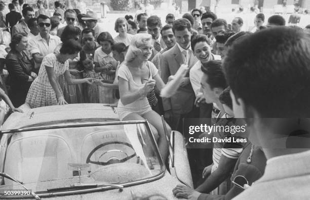 Singer Juli Reding sitting on her car while she signs autographs for her fans during her visit.