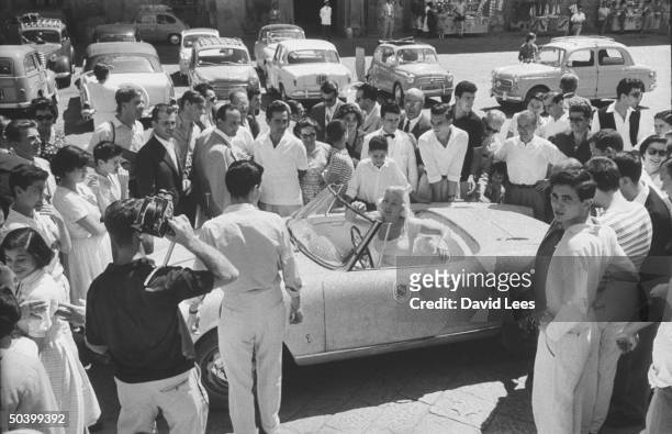 Singer Juli Reding sitting in her car surrounded by fans during her visit.