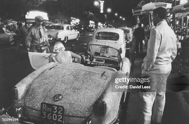 Singer Juli Reding getting out of her glitter painted car , with appreciative men watching.