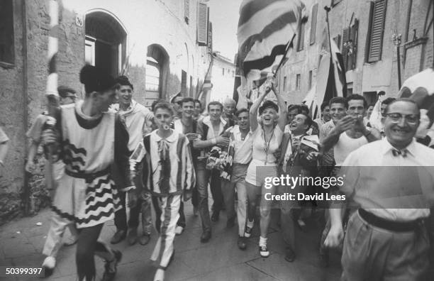 Singer Juli Reding carrying an Italian flag as she walks down the street with a group of fans.