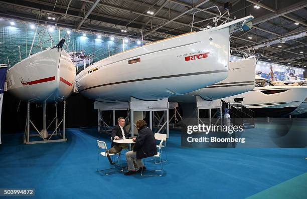 Visitors sit beneath a Jeanneau yacht at the 2016 London Boat Show at the ExCel exhibition centre in London, U.K., on Friday, Jan. 8, 2016. The event...