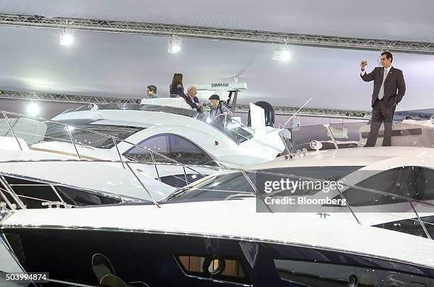 Visitor uses his smartphone to take a selfie photograph while standing aboard a Sunseeker International Ltd. Yacht on display at the 2016 London Boat...