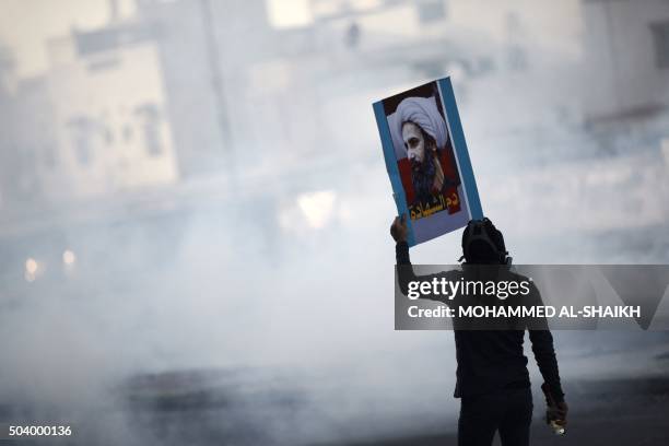 Bahraini protester holds a placard bearing a portrait of prominent Shiite Muslim cleric Nimr al-Nimr during clashes with riot police in the village...