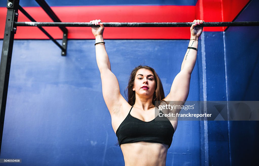 Fitness woman doing traction at the bar in a gym