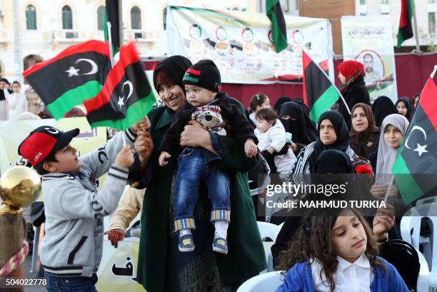 Libyan woman and children wave their national flags during a demonstration against a UN-sponsored agreement on forming a national unity government...