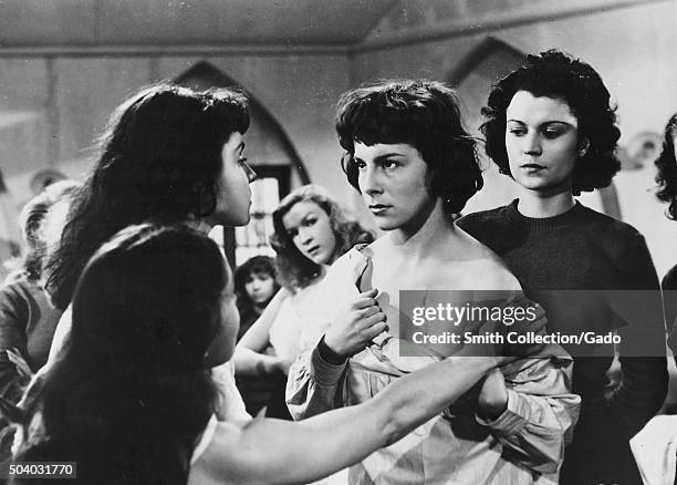 Au Royaume Des Cieux , movie still depicting two girls beginning to remove the blouse of another girl who looks concerned, from the film noir movie...