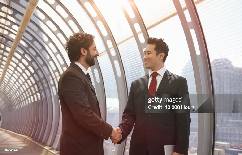Businessmen shaking hands in a futuristic tunnel