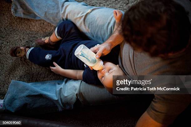 man feeding infant boy a bottle - bébé biberon photos et images de collection