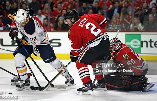 Zemgus Girgensons of the Buffalo Sabres tries to get off a shot against Duncan Keith and Corey Crawford of the Chicago Blackhawks at the United...