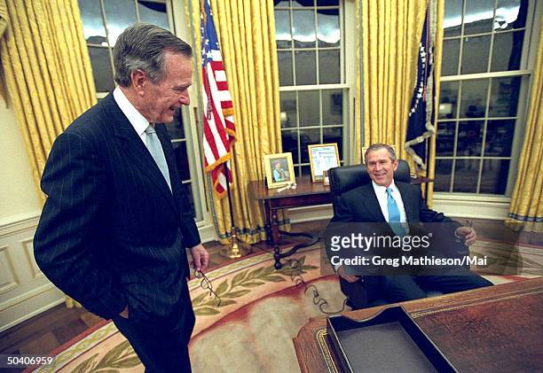 President George W. Bush talking w. His father, former President George H.W. Bush, while sitting at his desk in the Oval Office of the White House...