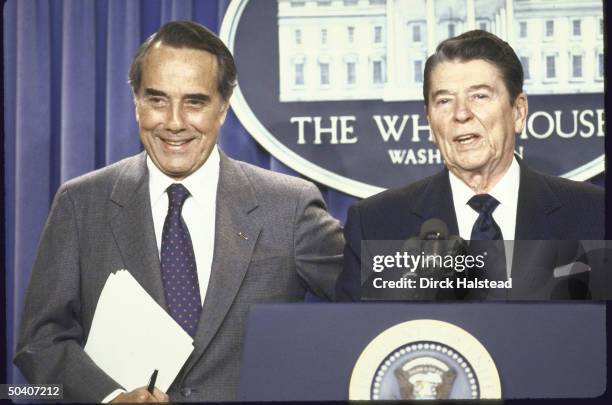 Pres. Ronald W. Reagan standing with Sen. Robert J. Dole of Kansas in the White House press briefing room.