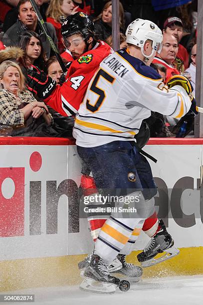 Rasmus Ristolainen of the Buffalo Sabres checks into Phillip Danault of the Chicago Blackhawks in the second period of the NHL game at the United...