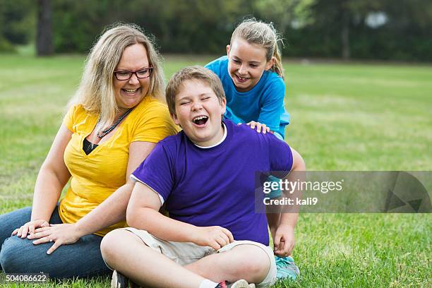 madre e due bambini ridono insieme nel parco - family with two children foto e immagini stock