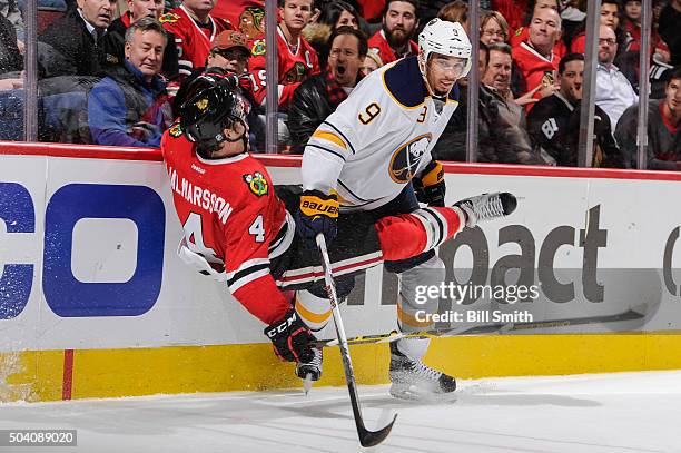 Niklas Hjalmarsson of the Chicago Blackhawks takes a hard hit from Evander Kane of the Buffalo Sabres in the third period of the NHL game at the...