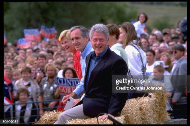 Pres. Bill Clinton joining Sen. Tom Harkin , sitting on hay bale during election campaign fish fry fundraiser.