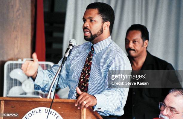 Congressional candidate Jesse Jackson Jr. Speaking at podium while his civil rights activist father, Rev. Jesse Jackson, stands behind him.