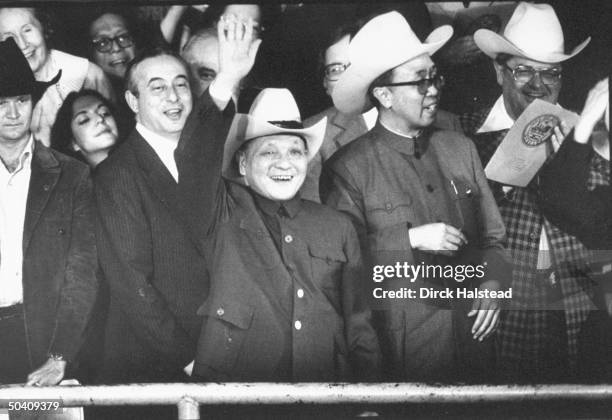 China's paramount leader Deng Xiaoping waving, wearing cowboy hat presented to him by his hosts, attending rodeo, entourage-in-tow, stop on his state...
