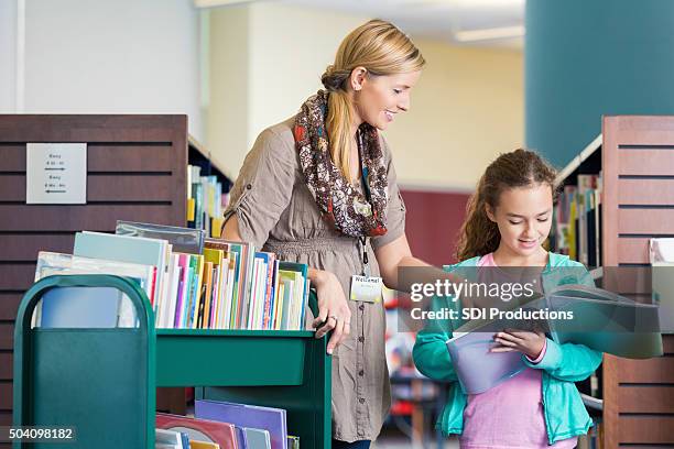 bibliotecario aiutare età scolare studente lettura libro in biblioteca - bibliotecario foto e immagini stock