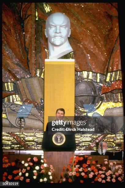 American President Reagan speaking at Moscow State University against backdrop of Lenin bust and mosaic featuring hammer and sickle, during summit,...