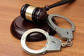 Handcuffs with gavel on a wood background