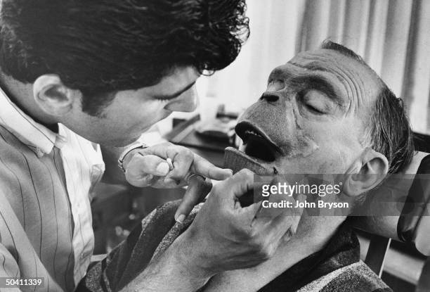 Foam-rubber make-up being applied to actor Maurice Evans; face for his simian role in film Planet of the Apes.