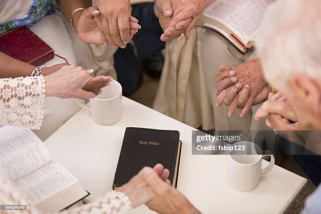 Senior adult friends pray during bible study group.