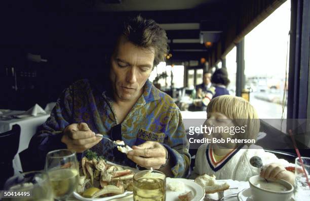 Watched by his three-year-old son Kyle, American actor Clint Eastwood eats a crab in a Fisherman's Wharf restuarant, San Francisco, California, 1971.