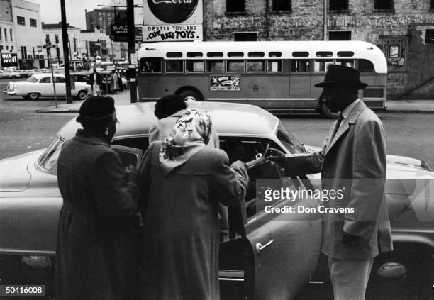 Group of African Americans get into an automoboile to car pool during the Montgomery bus boycott, Montgomery, Alabama, February 1956. An empty city...
