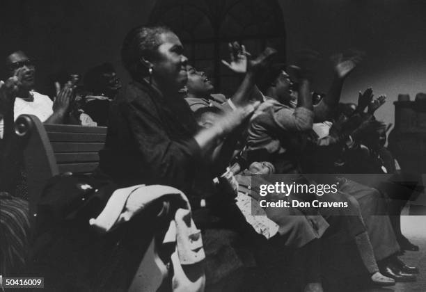 African American women and children, smiling, clapping enthusiastically, at church rally for bus boycott.