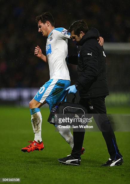 Florian Thauvin of Newcastle United hops off the pitch helped by a medical staff during the Emirates FA Cup Third Round match between Watford and...
