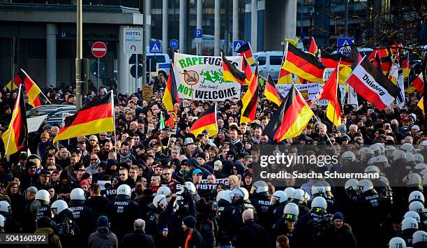 Protesters wave German flags, alongside a banner saying 'Rapefugees Not Welcome' as supporters of Pegida, Hogesa and other right-wing populist groups...