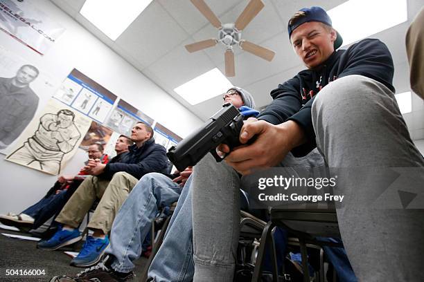 Jaden Adams person look over a unloaded semi automatic handgun during a class to obtain the Utah concealed gun carry permit, at Range Master of Utah,...