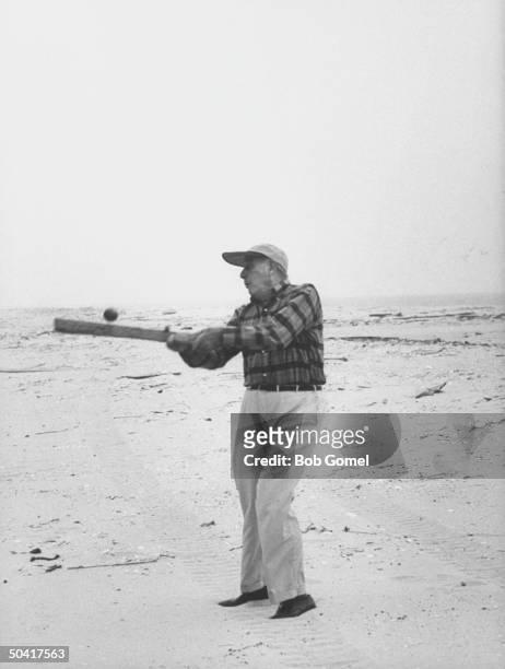 American public official and city planner Robert Moses swings at a ball on a Fire Island beach during a visit to a construction site, probably for...