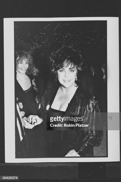 Actress Elizabeth Taylor at party she gave in honor of actor Roddy McDowall's new book of photographs; Shirlee Fonda smiling and holding her hand in...