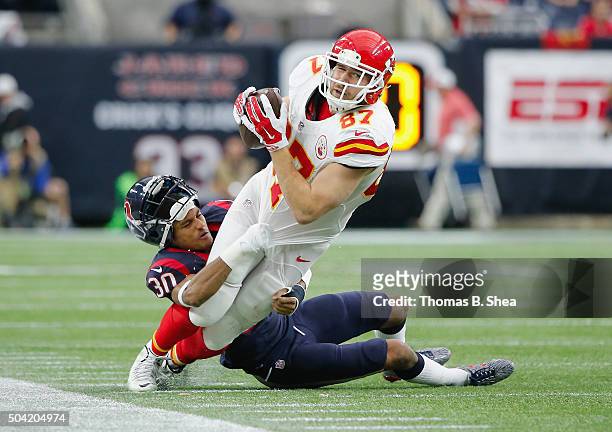 Travis Kelce of the Kansas City Chiefs is tackled by Kevin Johnson of the Houston Texans in the second quarter during the AFC Wild Card Playoff game...