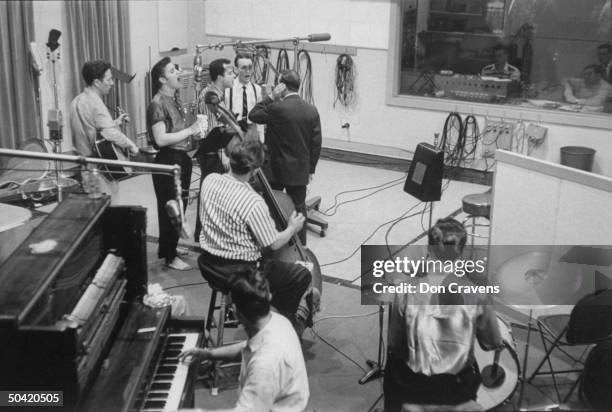 Elvis Presley recording a new song in an unidentified recording studio, backed up by the Jordanaires vocally, made up of Gordon Stoker, Neal...