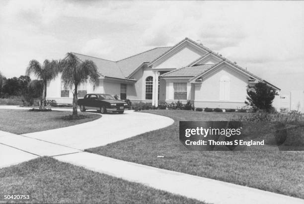 View of front yard and house of disgraced PTL minister Jim Bakker and his wife Tammy Faye, w. Mid-size sporty car in driveway.