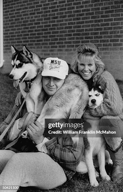 Green Bay Packers offensive lineman Tony Mandarich, w. One of his Siberian huskie dogs wrapped around his neck, as his fiancee Amber Ligon hugs the...