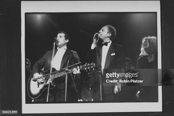 Singers Paul Simon & Art Garfunkel performing on stage w. Singer-songwriter Carole King in the bkgrd. During the Rock & Roll Hall of Fame induction...