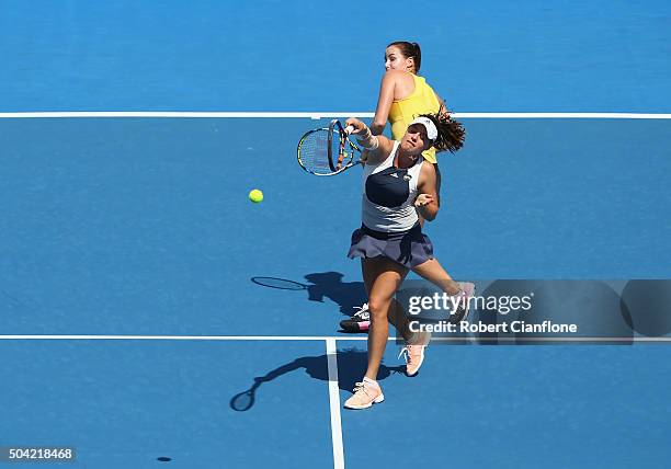 Kimberly Birrell of Australia plays an overhead shot as teammate Jarmila Wolfe of Australia looks on in the women's doubles match against Kateryna...